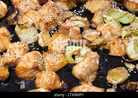 Cubes of teriyaki salmon covered in sesame seeds on oven pan coming out of air fryer Stock Photo