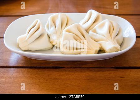 travel to Georgia - portion of boiled Khinkali (Georgian dumpling) on plate on wooden table in local cafe in Batumi city Stock Photo