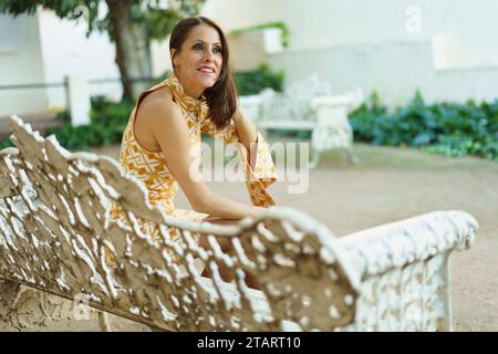 Concentrated young woman sitting on white bench in park Stock Photo