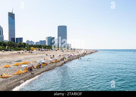 Batumi, Georgia - September 15, 2023: view of urban pebble beach and skyscrapers in Batumi city on sunny autumn day Stock Photo