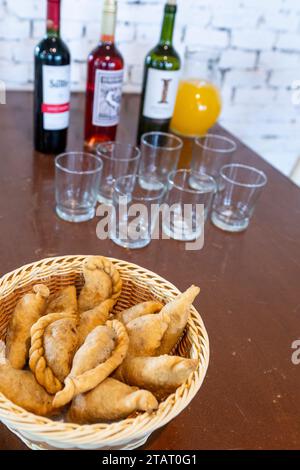 Argentina, Buenos Aires. Traditional savory meat empanadas, wine in the distance. Stock Photo