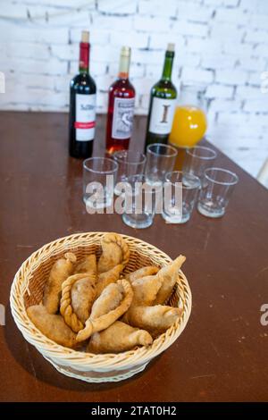Argentina, Buenos Aires. Traditional savory meat empanadas, wine in the distance. Stock Photo