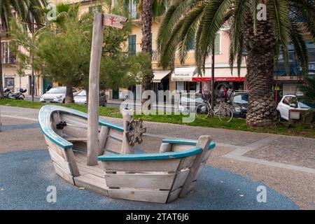 Wooden toy boat in a children's playground on the promenade of the popular holiday destination on the Italian Riviera di Ponente, Finale Ligure, Sav Stock Photo