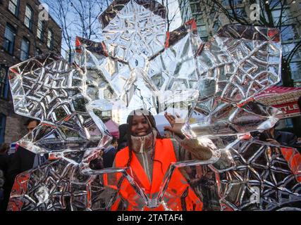 Vancouver, Canada. 2nd Dec, 2023. A resident poses behind an ice sculpture at the CandyTown festival in Vancouver, British Columbia, Canada, on Dec. 2, 2023. The CandyTown festival kicked off here on Saturday, during which streets in the downtown core were transformed into a winter wonderland with the theme of candy. Credit: Liang Sen/Xinhua/Alamy Live News Stock Photo
