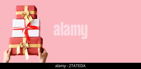 Hands with Christmas gifts on pink background with space for text Stock Photo