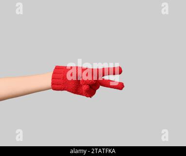 Hand in warm gloves showing victory gesture on grey background Stock Photo