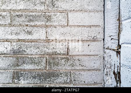 The faded white paint on the exterior brick wall of an abandoned building Stock Photo