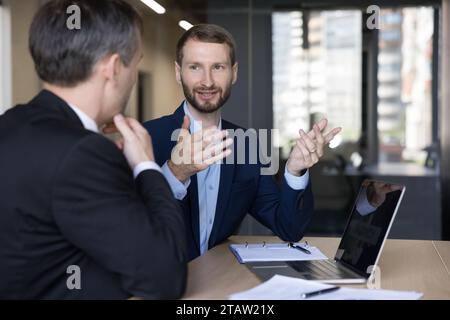 Two office man colleagues discuss business project use laptop Stock Photo