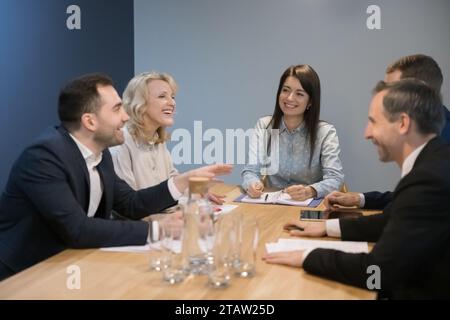 Businesspeople sit at office desk talk, laugh, discussing business ideas Stock Photo