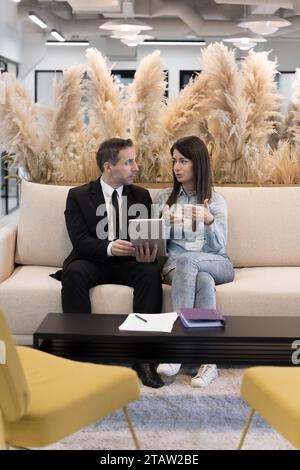Mature and young colleagues using modern application on digital tablet Stock Photo