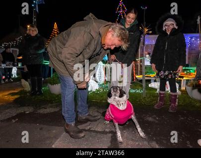 Bridport, Dorset, UK.  1st December 2023.  Actor Martin Clunes switches on the annual display of Christmas Lights which decorate the house of Monica and Rob Teague at White Close at Bradpole in Bridport, Dorset.  The display raises money for Julia’s House Children’s Hospice.  Martin Clunes talks to a dog.  Picture Credit: Graham Hunt/Alamy Live News Stock Photo