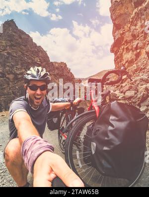 Male caucasian crazy cyclist by bicycle have funny expression outdoors pose on cycling trip. Travel around world cyclist experience documenting Stock Photo