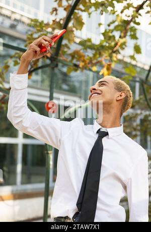 Beautiful young smiling black guy taking a selfie in the park, vertical photo Stock Photo