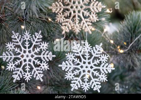 Artificial snowflakes decoration on the Christmas tree. Close up of natureal Christmas tree with decorations and garlands. Stock Photo