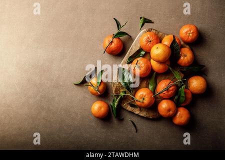 Mandarin oranges, clementines or tangerines with leaves on a dark background, top view Stock Photo