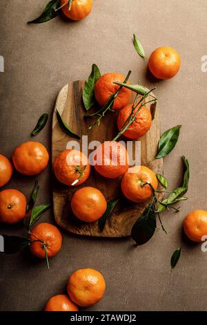 Mandarin oranges, clementines or tangerines with leaves on a dark background, top view Stock Photo