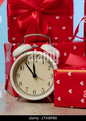 Alarm clock and stack of red gift boxes on blue background Stock Photo