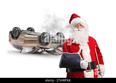 Santa claus with injured arm leaning on a crutch in front of a SUV turned upside down isolated on white background Stock Photo