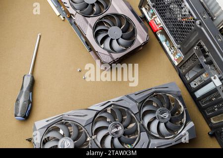 graphics card upgrading concept, two gaming graphics cards near desktop miditower ATX pc case on tan fabric background Stock Photo