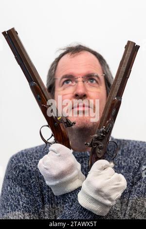 London, UK.  3 December 2023. A staff member presents 'A pair of 36 bore flintlock duelling pistols', 1816-20, by the London-maker Durs Egg, gunmaker to George IV, (Est. £14,000-18,000) at a preview of highlights from the upcoming Arms, Armour and Militaria sale at Olympia Auctions in west London.  The sale takes place on 6 December.  Credit: Stephen Chung / Alamy Live News Stock Photo