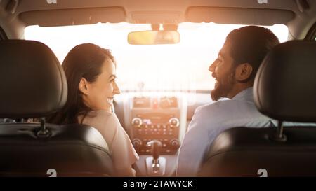 Arab couple conversing in car, sunlight behind Stock Photo