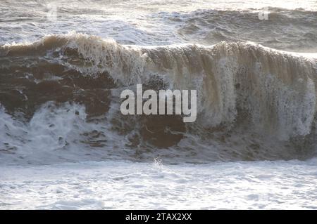 Stormy weather beside the sea. A large grey wave crashes onto the beach at West Bay on the English South Coast. Dorset, England, United Kingdom, UK. Stock Photo