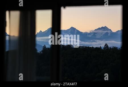 20 September 2023, Switzerland, Bern: A panorama of the three famous Swiss peaks Eiger (l-r), Mönch and Jungfrau can be seen from a window at sunrise. Photo: Jan Woitas/dpa Stock Photo