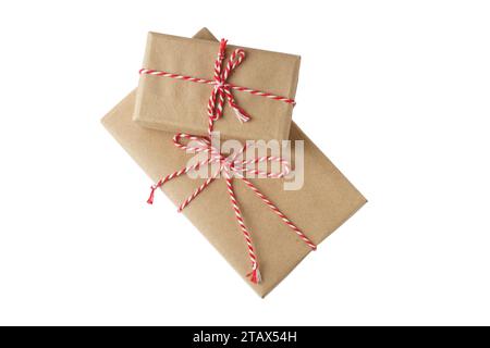 Two Christmas and New Year gift boxes wrapped in brown craft kraft paper with red and white baker's twine, ribbon bow isolated on white background Stock Photo
