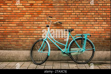 Blue vintage bicycle standing in front of an orange brick wall in the city of Bruges, Belgium. Stock Photo