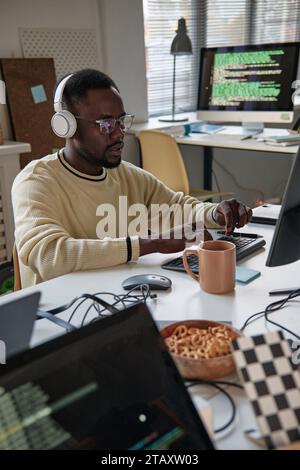 Back end developer listening to music in headphones when coding on laptop Stock Photo
