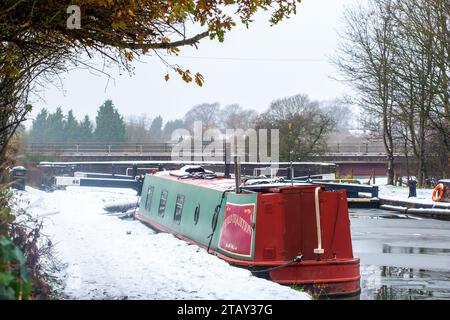 Canal narrowboat moored on the Trent and Mersey canal in the snow during winter at Wheelock locks Cheshire England UK Stock Photo
