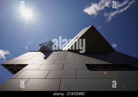 Futuristic architectural business building from low angle against blue sky with sun Stock Photo