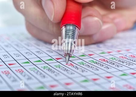 Hand with pen correction stock market report with stock data. Financial analysis and business concept. Close up Stock Photo