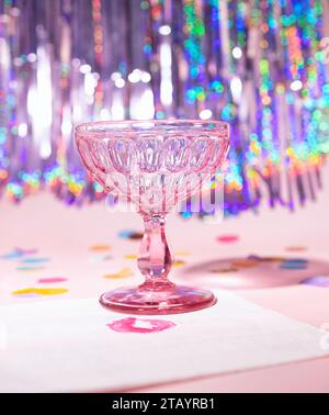 A Pink Champagne Vintage Coupe Glass with a Iridescent Tinsel background Party Scene Stock Photo
