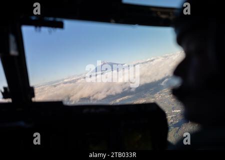 Mt. Fuji looms beyond the clouds as U.S. Marines with 2nd Battalion, 7th Marine Regiment ride aboard a U.S. Marine Corps MV-22B Osprey assigned to Marine Medium Tiltrotor Squadron (VMM) 262 during Stand-in Force Exercise 24 over Gotemba, Japan, Dec. 3, 2023. SIFEX 24 is a division-level exercise involving all elements of the Marine Air-Ground Task Force focused on strengthening multi-domain awareness, maneuver, and fires across a distributed maritime environment. 2/7 is forward deployed in the Indo-Pacific under 4th Marine Regiment, 3d Marine Division as part of the Unit Deployment Program. (U Stock Photo