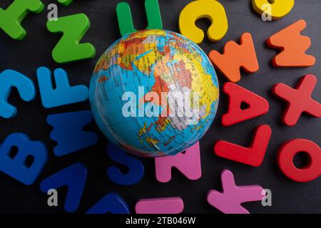 Earth globe model on colorful letters on a black background Stock Photo