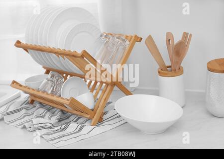 Drying rack with clean dishes on light table Stock Photo