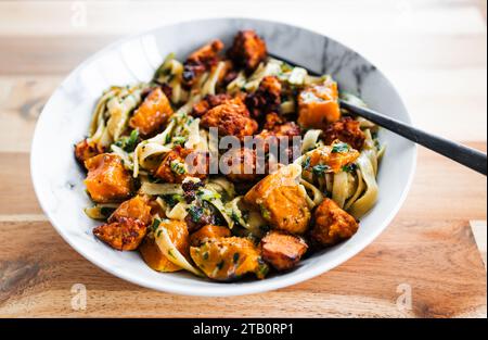 plant-based fettuccine pasta with spinach pumpkin and tofu chunks, healthy vegan food recipes Stock Photo