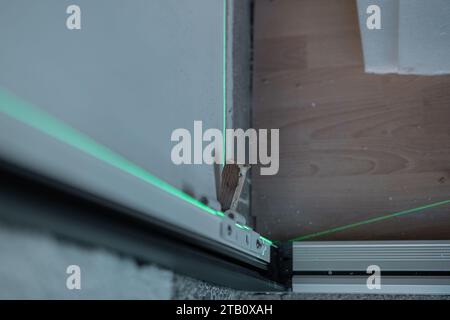Laser used for aligning door frame, which is being installed in a house. Green laser as a good level aid while installing different things around the Stock Photo