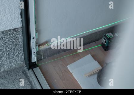 Laser used for aligning door frame, which is being installed in a house. Green laser as a good level aid while installing different things around the Stock Photo