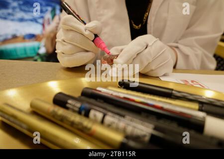 Mexico City, Mexico. 03rd Dec, 2023. Guadalupe Navarro Mabarak, a young Mexican-Lebanese illustration specialist and graduate from the Faculty of Arts and Design at the National Autonomous University of Mexico, is hand-personalizing a perfume from the Italian brand Dolce & Gabbana with acrylic paint pens at El Palacio de Hierro department store in Mexico City, Mexico, on December 24, through the agency Design Emergency Studio. (Photo by Gerardo Vieyra/NurPhoto)0 Credit: NurPhoto SRL/Alamy Live News Stock Photo