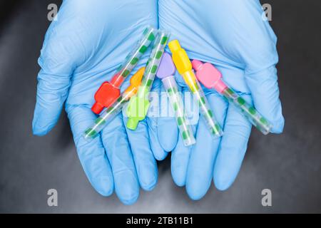 Close up Interdental Toothbrushes in dentists hands in rubber gloves on black background. Stock Photo