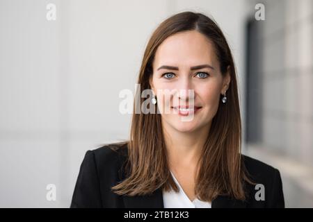 Attractive dark-haired businesswoman in office suit looks at camera Stock Photo