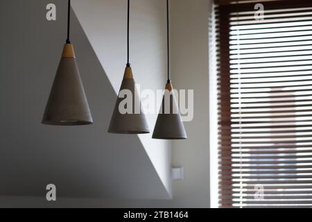 Cone shaped lights made of concrete. A set of three modern minimalistic futuristic ceiling lights in the living room. Stock Photo