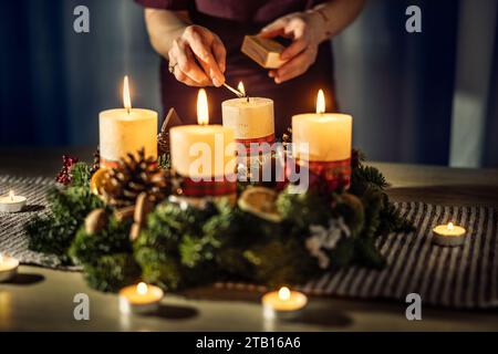 A woman lights the last fourth candle on an Advent wreath during Christmas Eve. Stock Photo