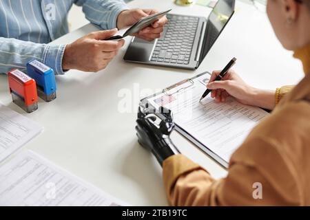 High angle view of woman with prosthetic arm filing documents for visa during meeting with manager Stock Photo