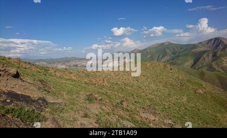 Herd of sheep grazing on the green meadows with mountains. A flock of sheep in the heights of the Iranian plateau. Lorestan. Durood Stock Photo