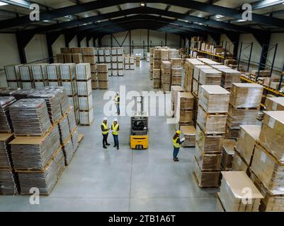 Top view of warehouse workers in warehouse. Team of warehouse workers preparing products for shipment, checking delivery, stock in warehouse. Stock Photo