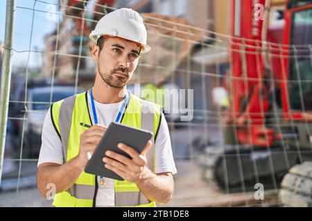 Young hispanic man architect drawing on touchpad at street Stock Photo