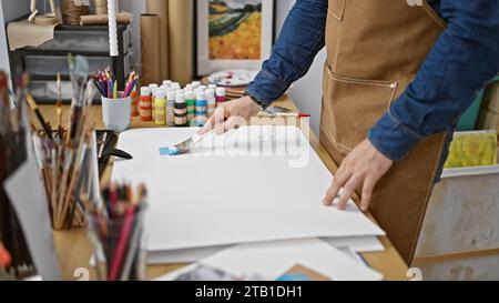 Passionate young hispanic man artist fervently drawing with brush at art studio, deeply immersed in his craft Stock Photo